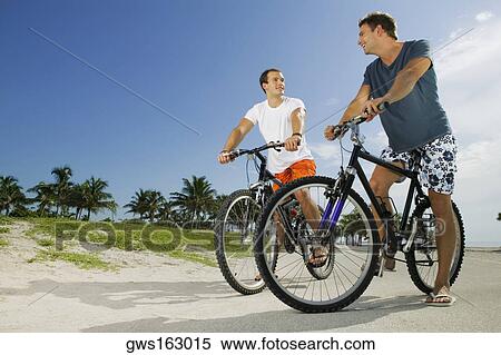 Low angle view of two young men on bicycles View Large Photo Image Stock Photography - Low angle view of two young men on bicycles. Fotosearch