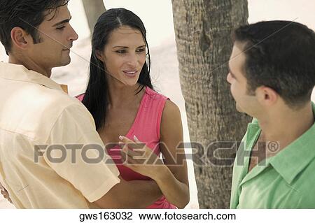 Stock Image - Mid adult man with a young woman and a young man looking at each other. Fotosearch