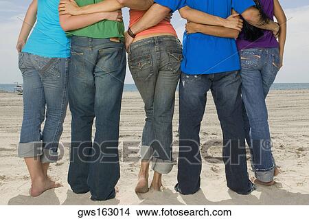 Rear view of five people standing on the beach View Large Photo Image Picture - Rear view of five people standing on the beach. Fotosearch