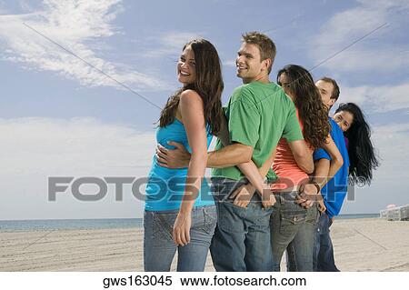 Rear view of five people standing on the beach View Large Photo Image Stock Photography - Rear view of five people standing on the beach. Fotosearch