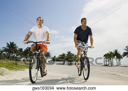Two young men cycling on the road View Large Photo Image Picture - Two young men cycling on the road. Fotosearch