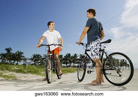Two young men on bicycles View Large Photo Image Stock Image - Two young men on bicycles. Fotosearch