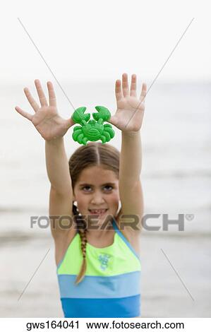 Stock Image - Close-up of a girl holding a toy on the beach . Fotosearch