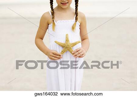 Close-up of a girl standing on the beach and holding a starfish View Large Photo Image Stock Image - Close-up of a girl standing on the beach and holding a starfish. Fotosearch