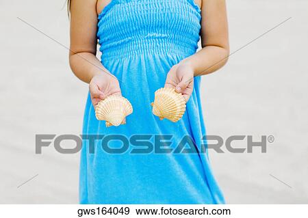 Mid section view of a girl standing on the beach and holding shells View Large Photo Image Stock Photo - Mid section view of a girl standing on the beach and holding shells. Fotosearch