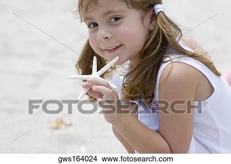 Portrait of a girl playing with a starfish on the beach View Large Photo Image Picture - Portrait of a girl playing with a starfish on the beach. Fotosearch