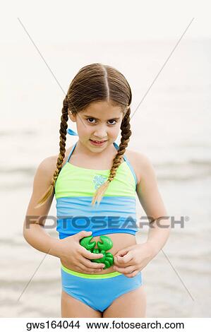 Portrait of a girl standing on the beach and holding a toy View Large Photo Image Picture - Portrait of a girl standing on the beach and holding a toy. Fotosearch