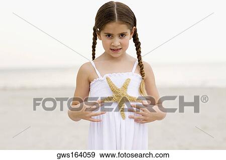 Portrait of a girl standing on the beach and holding a starfish View Large Photo Image Stock Photo - Portrait of a girl standing on the beach and holding a starfish. Fotosearch