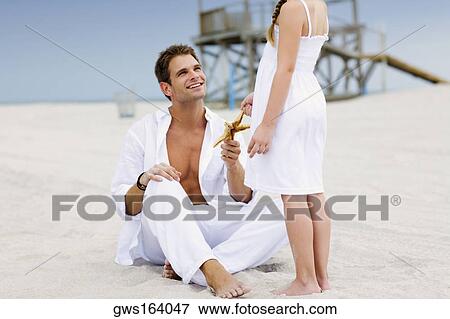 Young man giving a starfish to his daughter View Large Photo Image Stock Photo - Young man giving a starfish to his daughter. Fotosearch