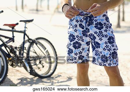 Low section view of a man holding a pair of sunglasses View Large Photo Image Picture - Low section view of a man holding a pair of sunglasses. Fotosearch