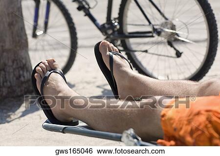 Low section view of a man relaxing on the beach View Large Photo Image Stock Photograph - Low section view of a man relaxing on the beach. Fotosearch