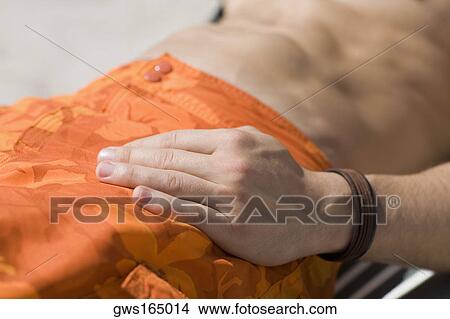 Mid section view of a man relaxing on a lounge chair View Large Photo Image Picture - Mid section view of a man relaxing on a lounge chair. Fotosearch