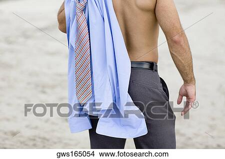 Mid section view of a man standing on the beach with a shirt and tie on his shoulder View Large Photo Image Picture - Mid section view of a man standing on the beach with a shirt and tie on his shoulder. Fotosearch