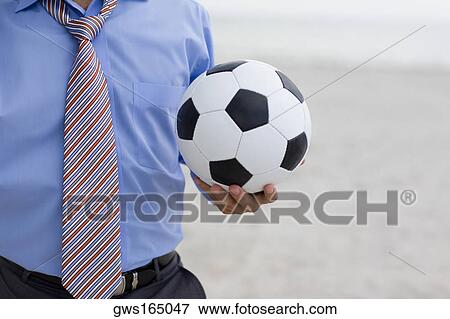 Mid section view of a man standing on the beach and holding a soccer ball View Large Photo Image Stock Photo - Mid section view of a man standing on the beach and holding a soccer ball. Fotosearch