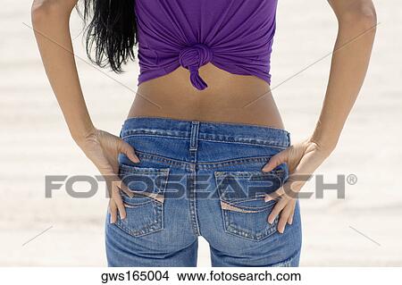 Mid section view of a young woman standing on the beach with her hands on her hips View Large Photo Image Picture - Mid section view of a young woman standing on the beach with her hands on her hips. Fotosearch