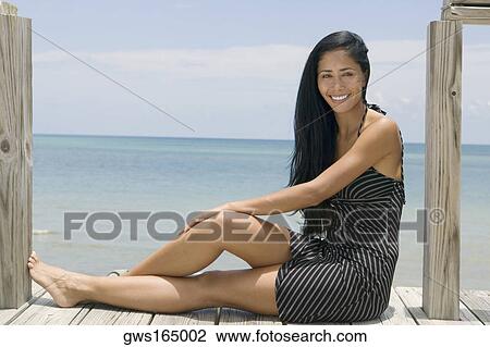 Portrait of a young woman sitting on a pier and smiling View Large Photo Image Stock Image - Portrait of a young woman sitting on a pier and smiling. Fotosearch