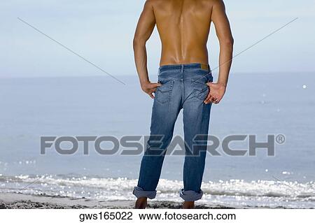 Rear view of a mid adult man standing on the beach View Large Photo Image Stock Image - Rear view of a mid adult man standing on the beach. Fotosearch