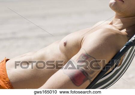 Stock Image - Side profile of a man relaxing on the beach. Fotosearch