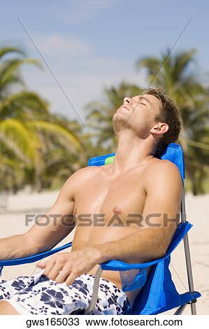 Stock Photo Of Young Man Relaxing On A Lounge Chair At The Beach Stock Photo Young Man Relaxing On A Lounge Chair At The Beach Fotosearch
