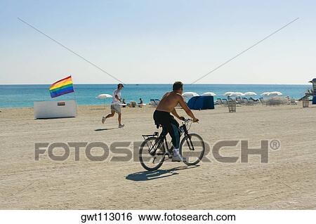 Side profile of a man cycling on the beach View Large Photo Image Stock Photograph - Side profile of a man cycling on the beach. Fotosearch