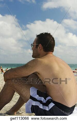 Side profile of a mid adult man sitting on the beach View Large Photo Image Stock Photograph - Side profile of a mid adult man sitting on the beach. Fotosearch