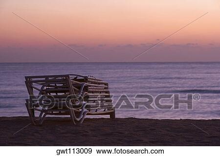Stack of folded lounge chairs on the beach View Large Photo Image Stock Photo - Stack of folded lounge chairs on the beach. Fotosearch