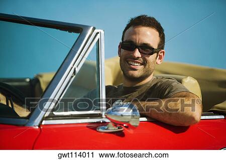 Stock Image - Close-up of a mid adult man sitting in a convertible car, Miami, Florida, USA. Fotosearch