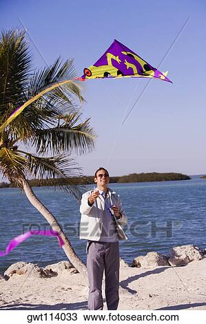 Stock Image - Mid adult man flying a kite. Fotosearch