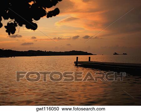 Stock Image - Pier in the sea at sunset. Fotosearch