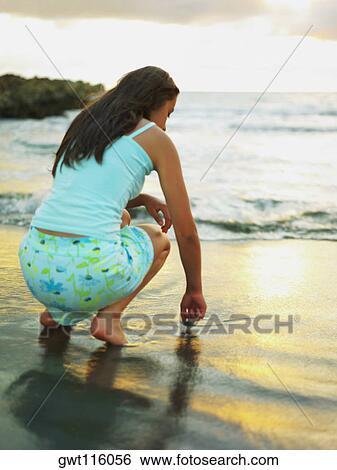 Rear view of a teenage girl drawing in the sand with her finger View Large Photo Image Stock Photograph - Rear view of a teenage girl drawing in the sand with her finger. Fotosearch