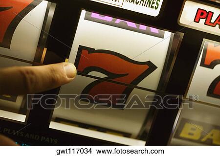 Picture - Close-up of a person's finger operating a slot machine, Las Vegas, Nevada, USA. Fotosearch