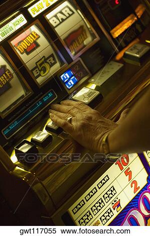 Stock Photography - High angle view of a woman's hand operating a slot machine, Las Vegas, Nevada, USA. Fotosearch