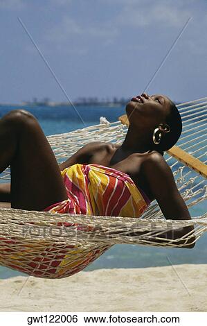 Stock Photograph - Desiree Lynes wearing a sarong lies on a hammock, Crystal Palace Hotel, Nassau, Bermuda. Fotosearch
