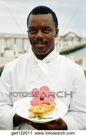 Stock Image - Phillip Bethel holding a garnished dish, Abaco, Bahamas. Fotosearch