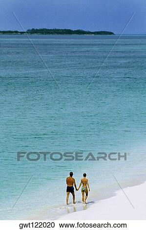 Rear view of a couple taking a stroll on a seashore, Paradise Island, Nassau, Bahamas View Large Photo Image Stock Image - Rear view of a couple taking a stroll on a seashore, Paradise Island, Nassau, Bahamas. Fotosearch