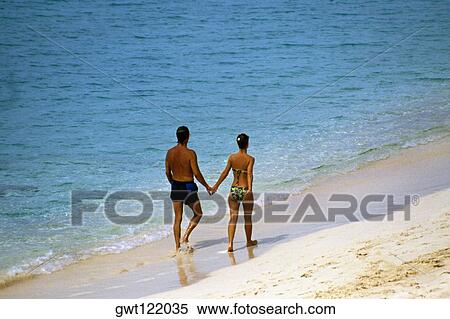 Stock Photography - Rear view of a couple walking along the seacoast in swimsuit, Paradise Island, Nassau, Bahamas. Fotosearch