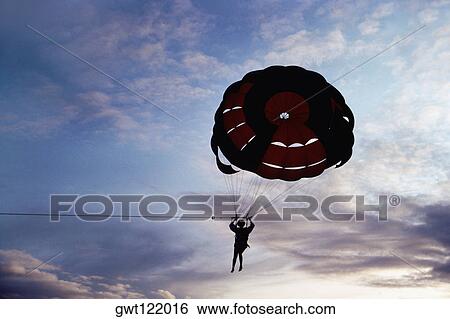Stock Photograph - Silhouette of a person parasailing at sunset, Bahamas. Fotosearch