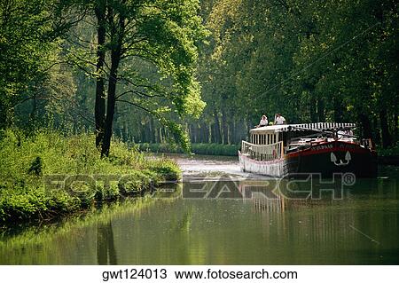 Hotel barge passing through a river with trees on either side, Burgundy River, France View Large Photo Image Stock Image - Hotel barge passing through a river with trees on either side, Burgundy River, France. Fotosearch