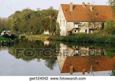 View of a barge moving upstream and passing by a farmhouse, Burgundy River, France View Large Photo Image Stock Image - View of a barge moving upstream and passing by a farmhouse, Burgundy River, France. Fotosearch