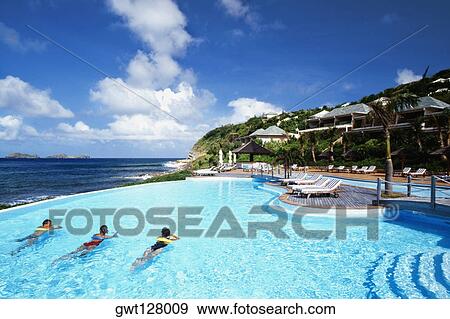 Stock Photo - Three people relaxing in a swimming pool of a resort near a seashore, St. Bant's. Fotosearch