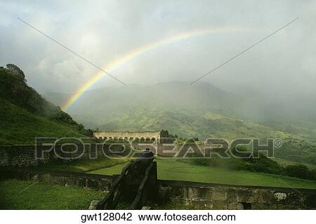 View of a beautiful rainbow arched amidst vast and lush meadows, St. Kitts, Leeward Islands, Caribbean View Large Photo Image Stock Image - View of a beautiful rainbow arched amidst vast and lush meadows, St. Kitts, Leeward Islands, Caribbean. Fotosearch
