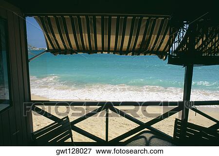 Stock Photo - View of a calm beach from the deck of a seaside restaurant, St. Maarten, Caribbean. Fotosearch
