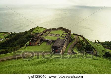 Stock Image - View of a lush meadow overlooking a vast sea, St. Kitts, Leeward Islands, Caribbean.. Fotosearch