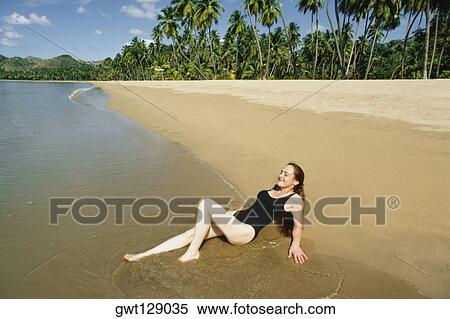 Stock Photography - Side view of a woman relaxing on a beach, Mayaquez beach, San Juan, Puerto Rico. Fotosearch
