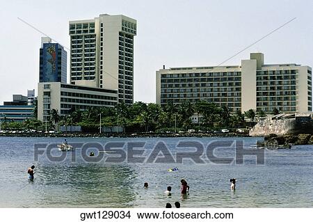 Side view of commercial buildings with a lake in the foreground, San Juan, Puerto Rico View Large Photo Image Picture - Side view of commercial buildings with a lake in the foreground, San Juan, Puerto Rico. Fotosearch
