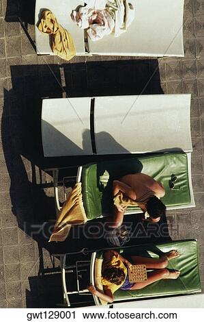 Stock Image - Top view of women sunbathing on deck chairs, San Juan, Puerto Rico. Fotosearch