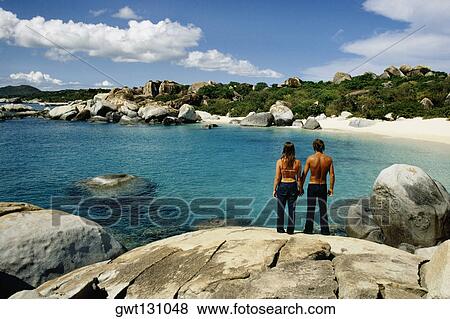 Rear view of a couple on the rocks, Virgin Gorda, Virgin Islands View Large Photo Image Stock Photo - Rear view of a couple on the rocks, Virgin Gorda, Virgin Islands. Fotosearch