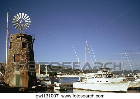 Stock Photo - View of boats at a harbor near a windmill, St. Croix, Virgin Islands. Fotosearch