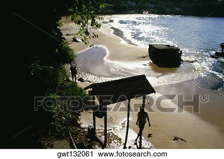 Stock Image - Silhouette of two men seen on a remote and calm beach, St. Lucia. Fotosearch