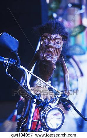 Close-up of a wooden sculpture of a devil sitting on motorcycle, Bali, Indonesia View Large Photo Image Stock Photo - Close-up of a wooden sculpture of a devil sitting on motorcycle, Bali, Indonesia. Fotosearch